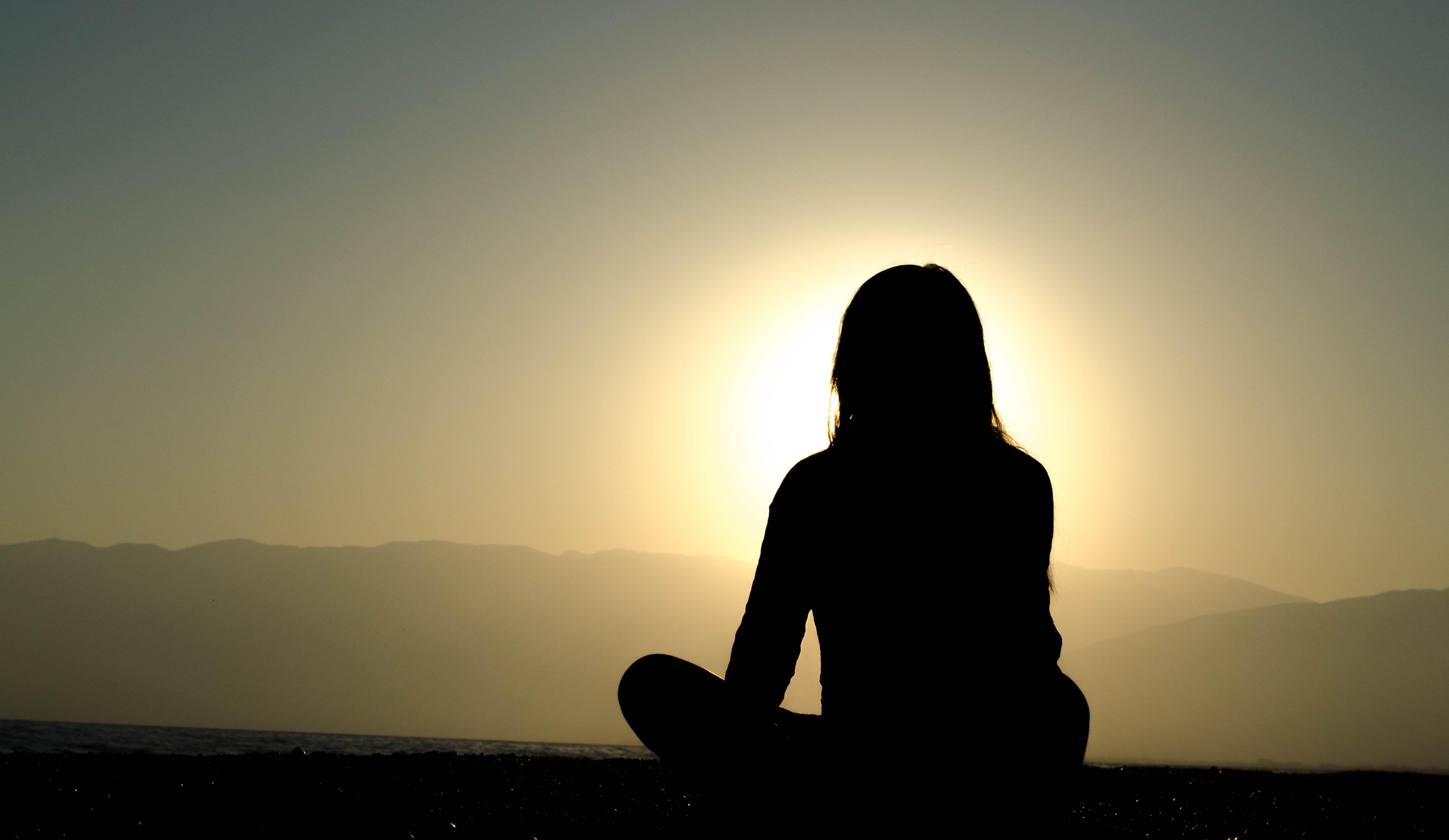 woman meditating before rising sun