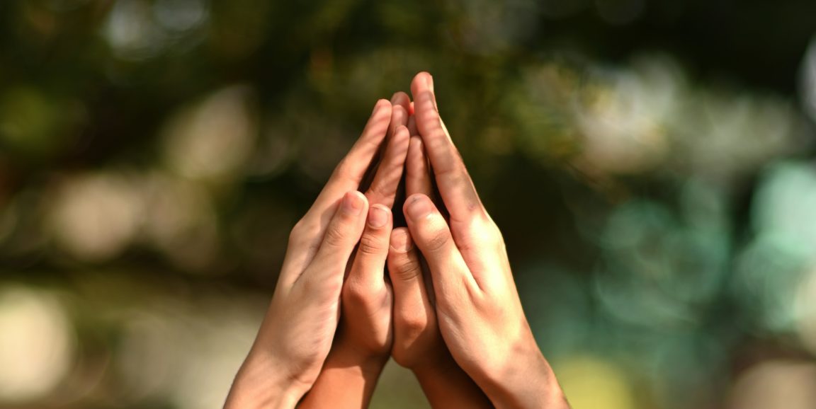 Four hands come together in prayer