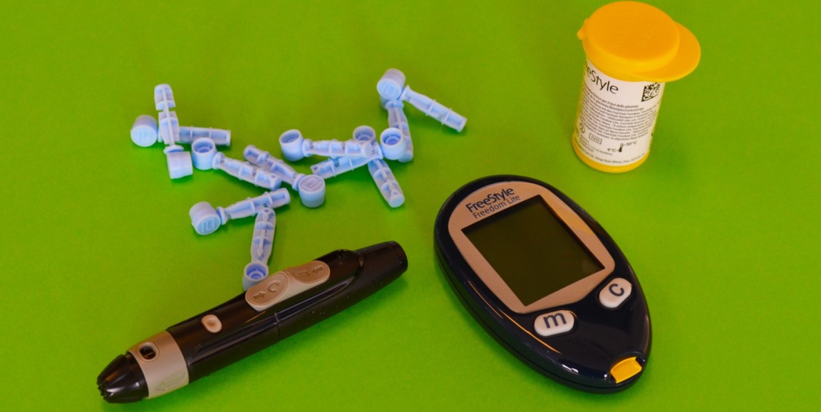 Tools and monitors used to track glucose and diabetes care are on a green background